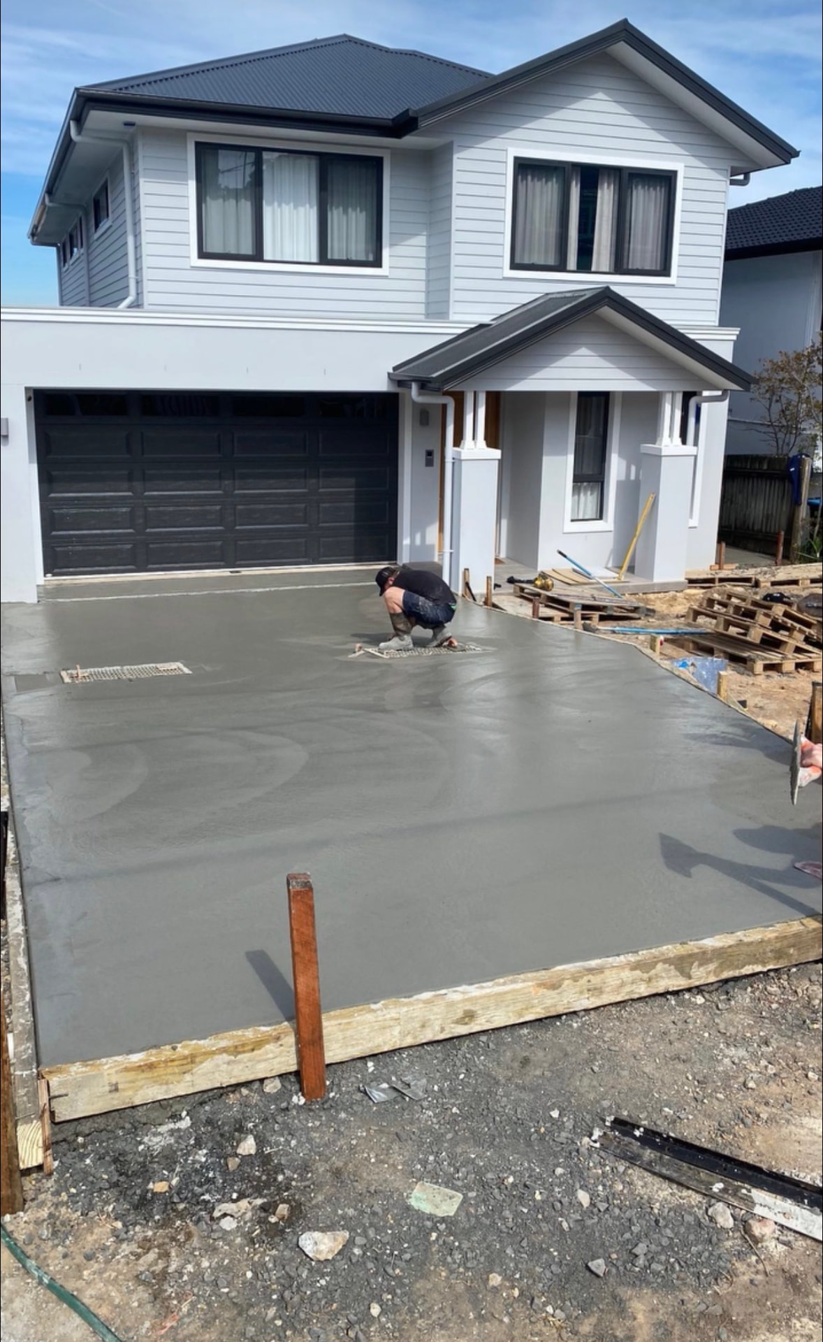 New concrete driveway being finished in front of a two-storey home